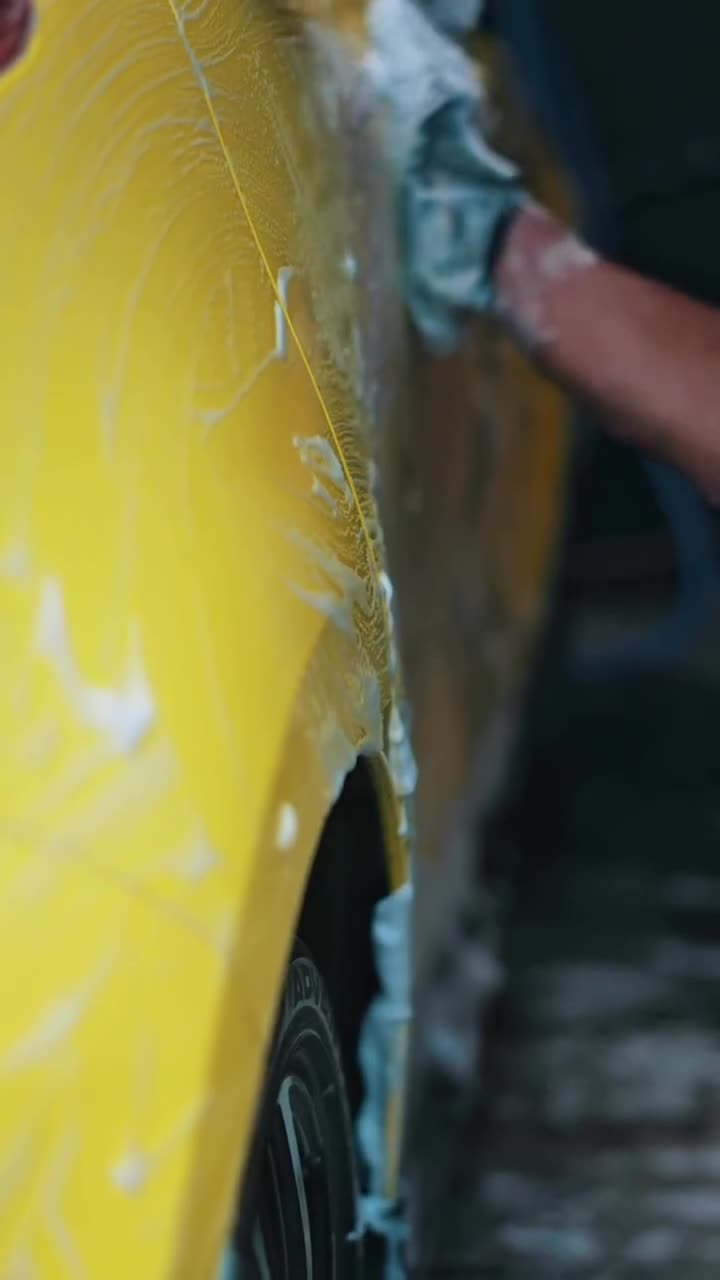 Lavado a mano con espuma de un auto amarillo en la sucursal